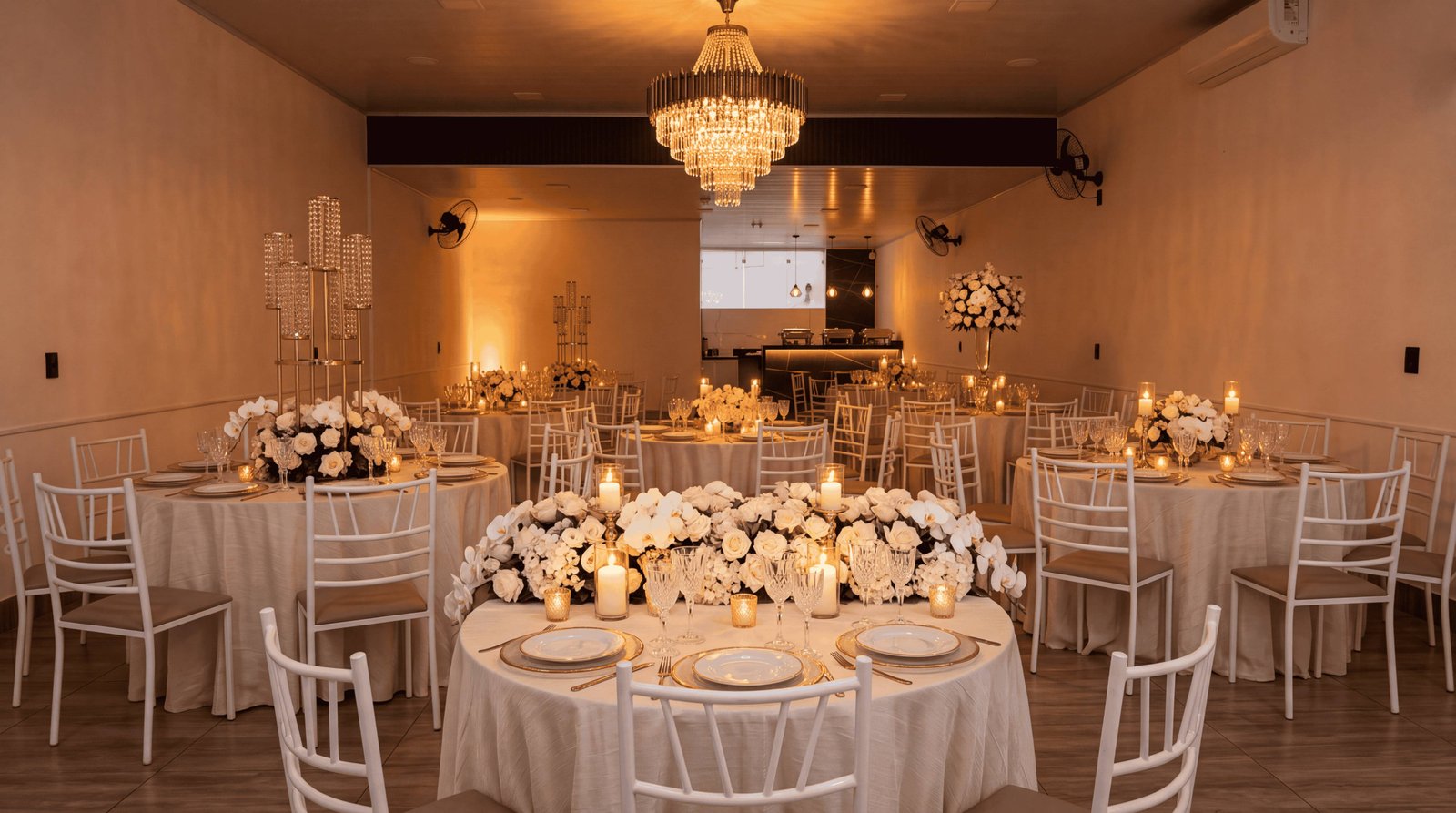 Salão de eventos iluminado com mesas postas para uma recepção